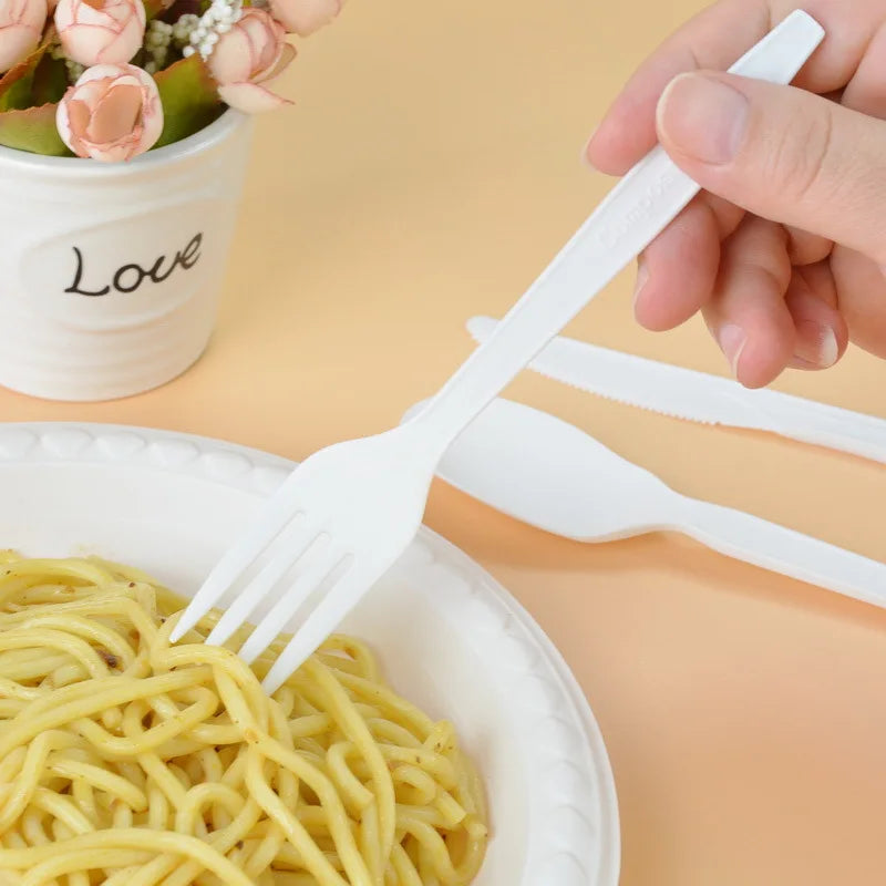 Person holding a white plastic fork over a plate of spaghetti with a blurred background.