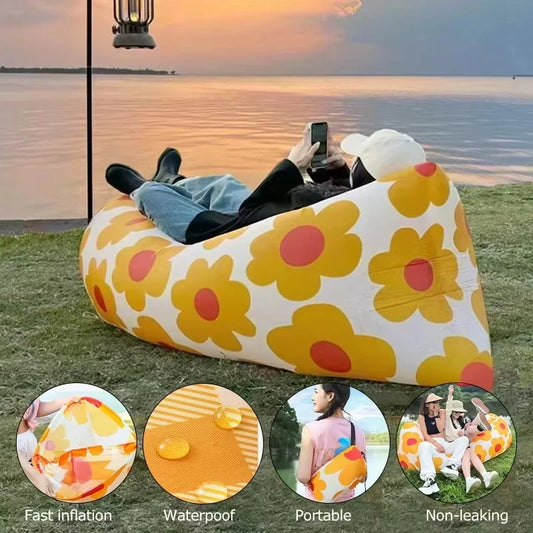 Inflatable floral-patterned air sofa with people using it by a lake at sunset.