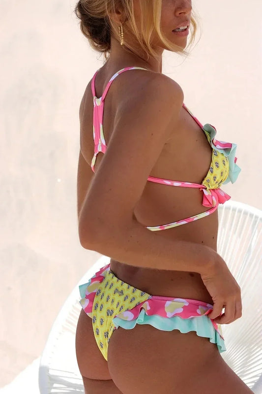 Woman wearing a colorful bikini with a light pink and yellow pattern on a white background
