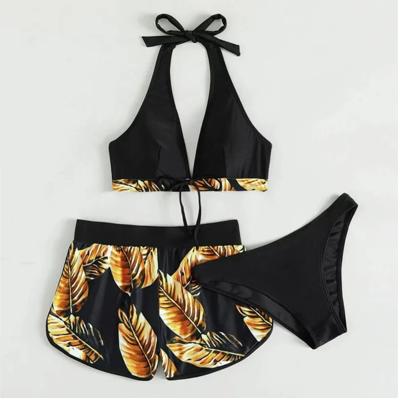 Black bikini set with gold leaf pattern on a light gray background