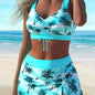 Woman wearing a blue palm tree print bikini set on a beach.