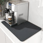 Espresso machine on a kitchen counter with a black spill mat underneath