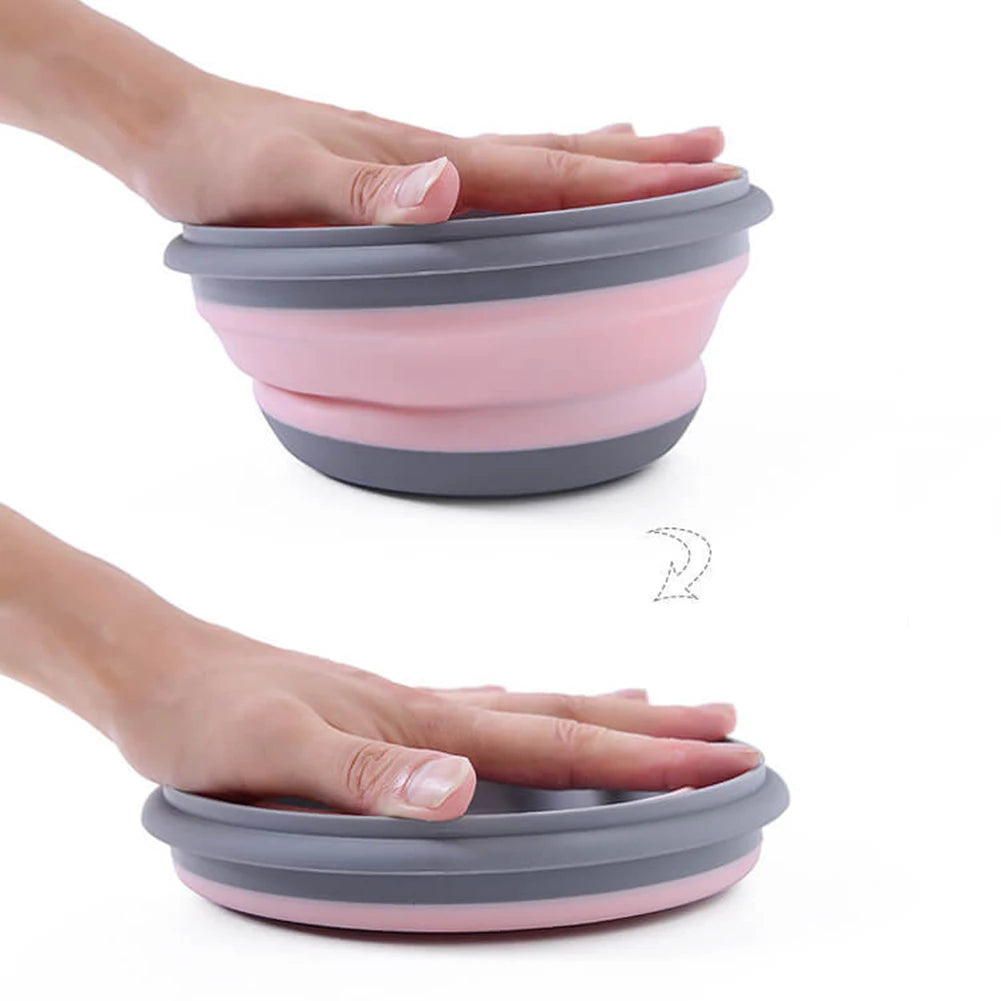 Collapsible pink and gray bowl being held by a person's hands on a white background