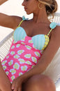 Woman wearing a colorful floral swimsuit sitting on a white chair.