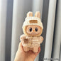 labubu  toy with bunny ears held in a hand against a neutral background