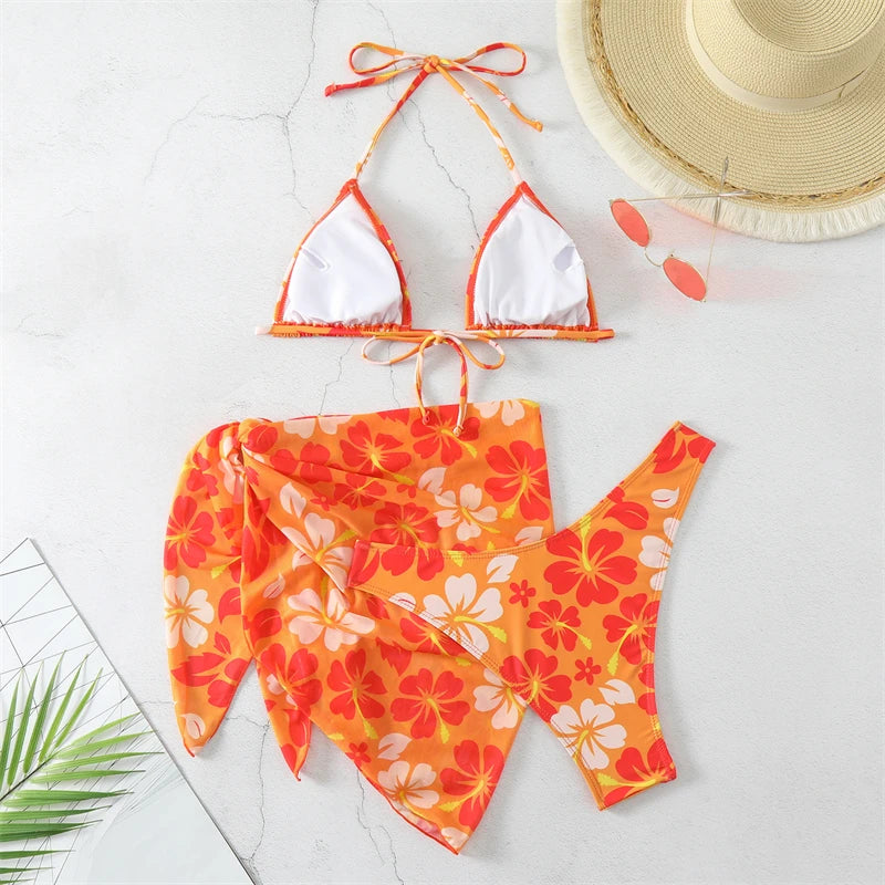 Orange and white floral bikini set with a straw hat on a light background