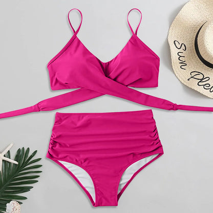 Pink bikini set with a straw hat and palm leaf on a light gray background