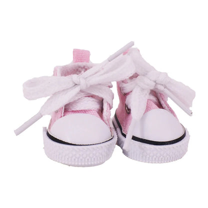 Pink baby sneakers with white laces on a white background