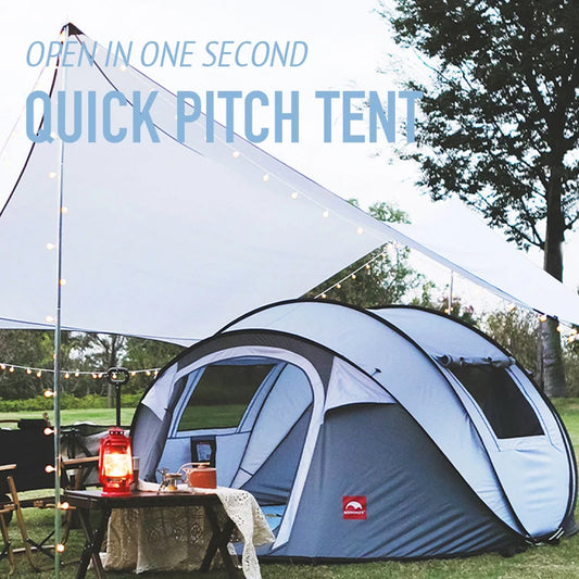 Quick pitch tent set up outdoors with a table and lantern, surrounded by trees.