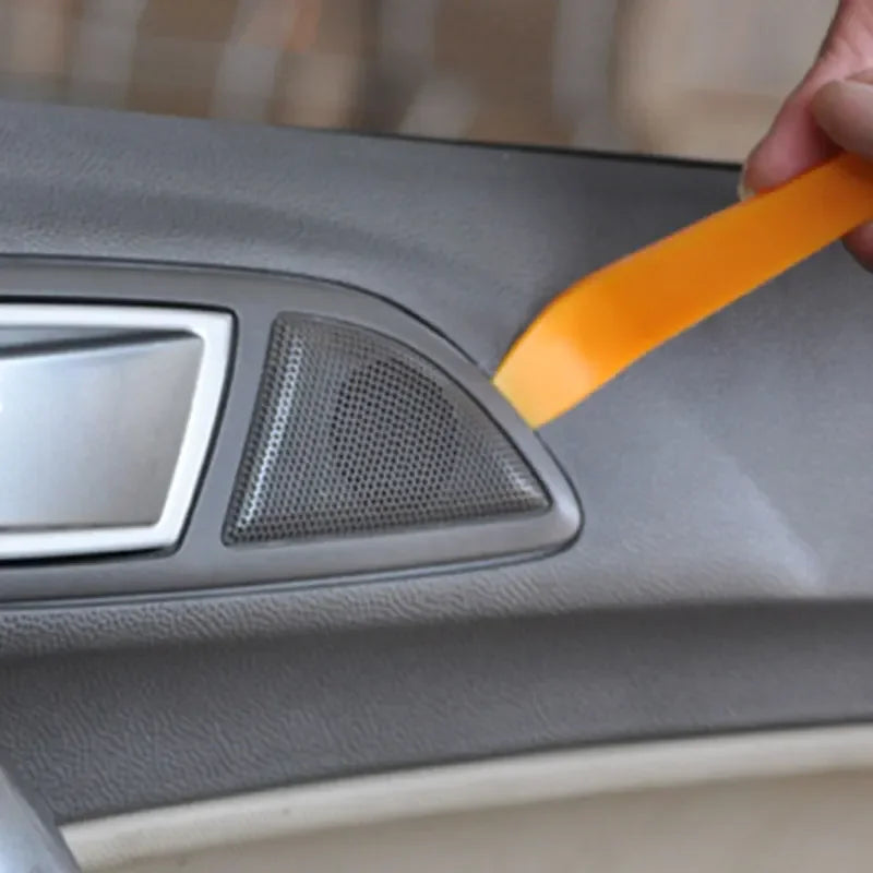 Person using an orange tool on a car's dashboard