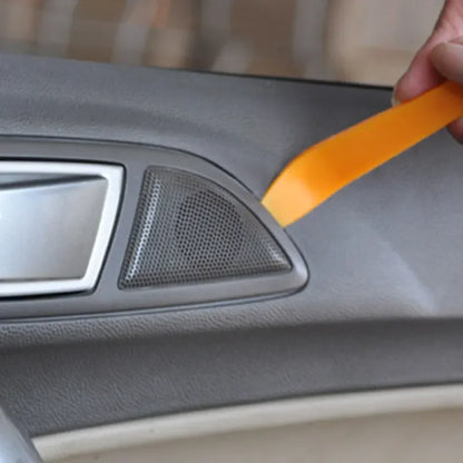 Person using an orange tool on a car's dashboard